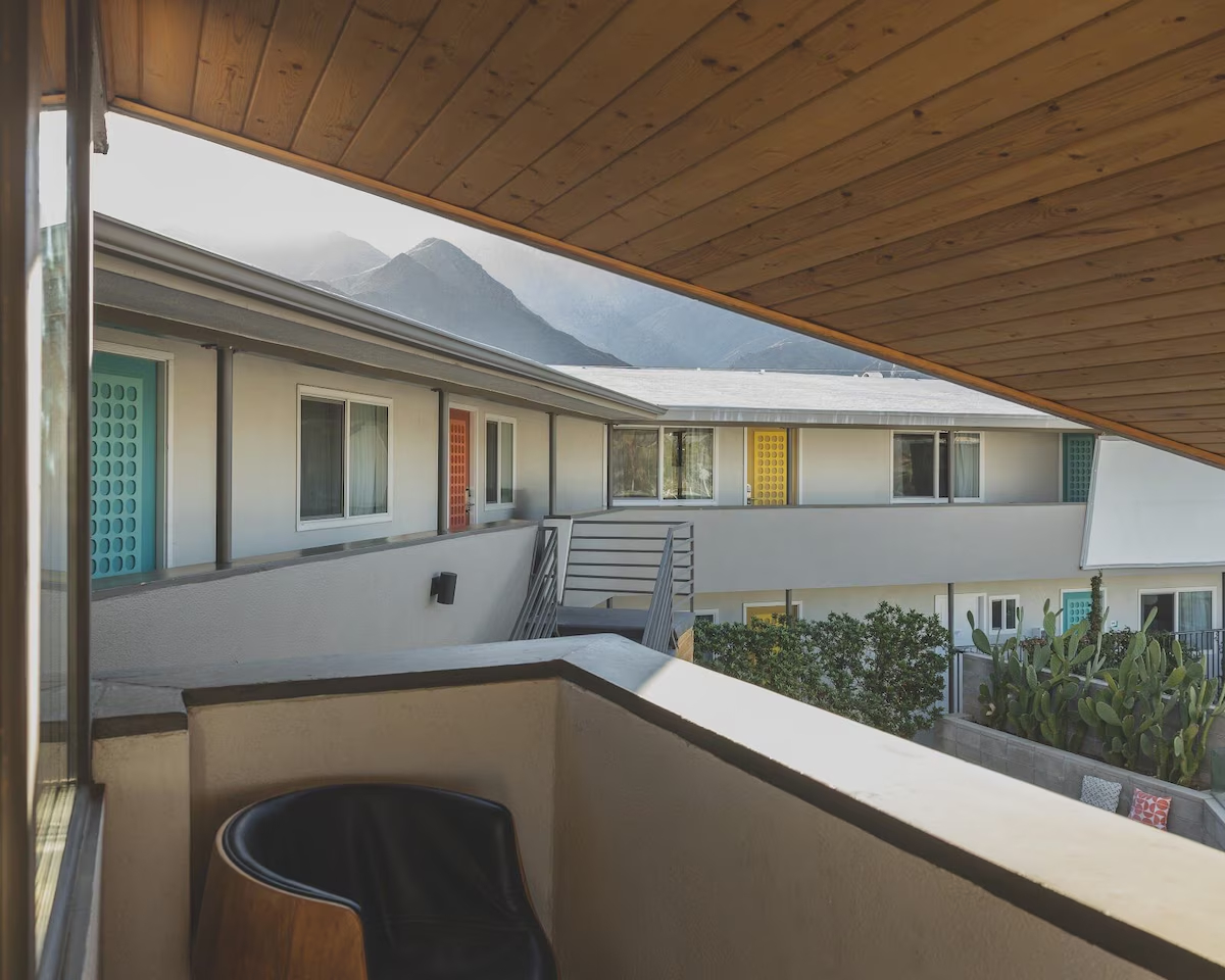 A balcony with a wooden ceiling and a view of a building and mountains.