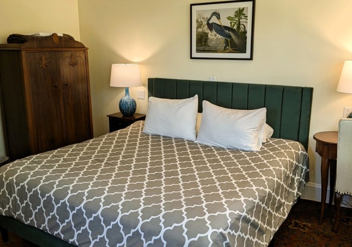 A hotel room with a bed, nightstands, lamps, and a wardrobe.