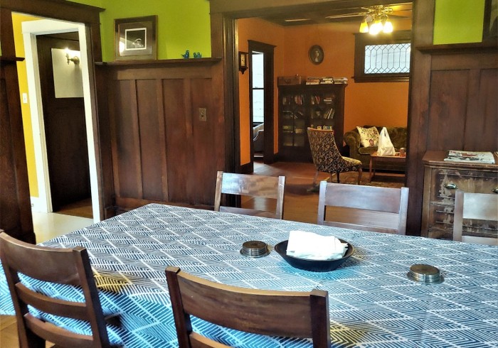 A dining area with a table and chairs in a room with wooden paneling and colorful walls.