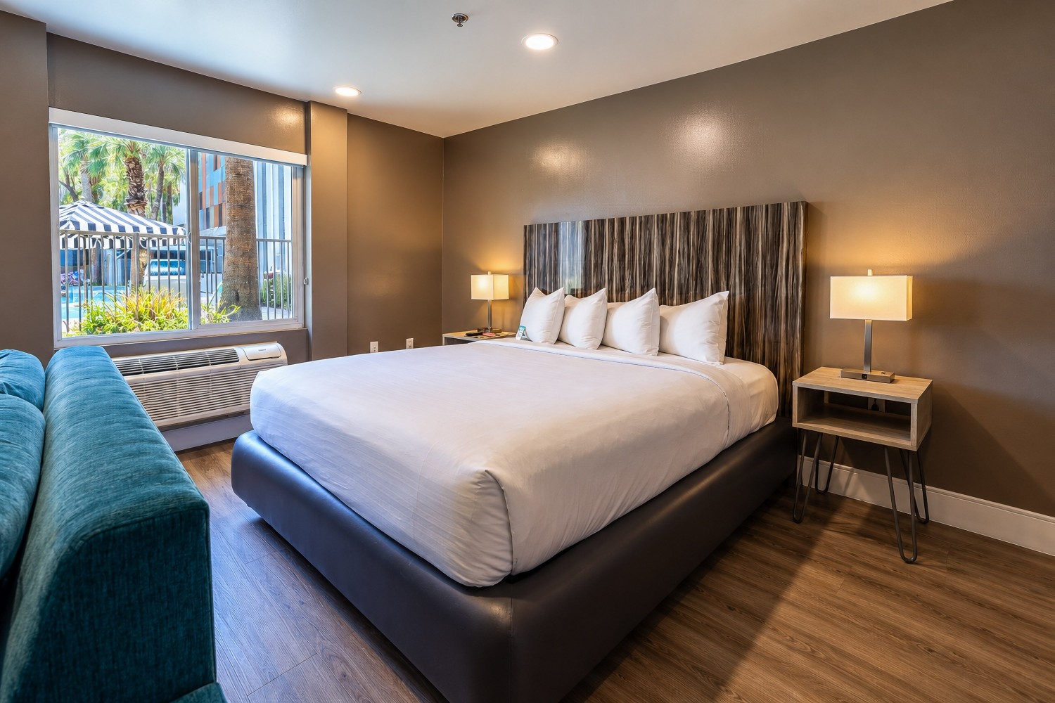 A hotel room with a large bed, sofa, and window